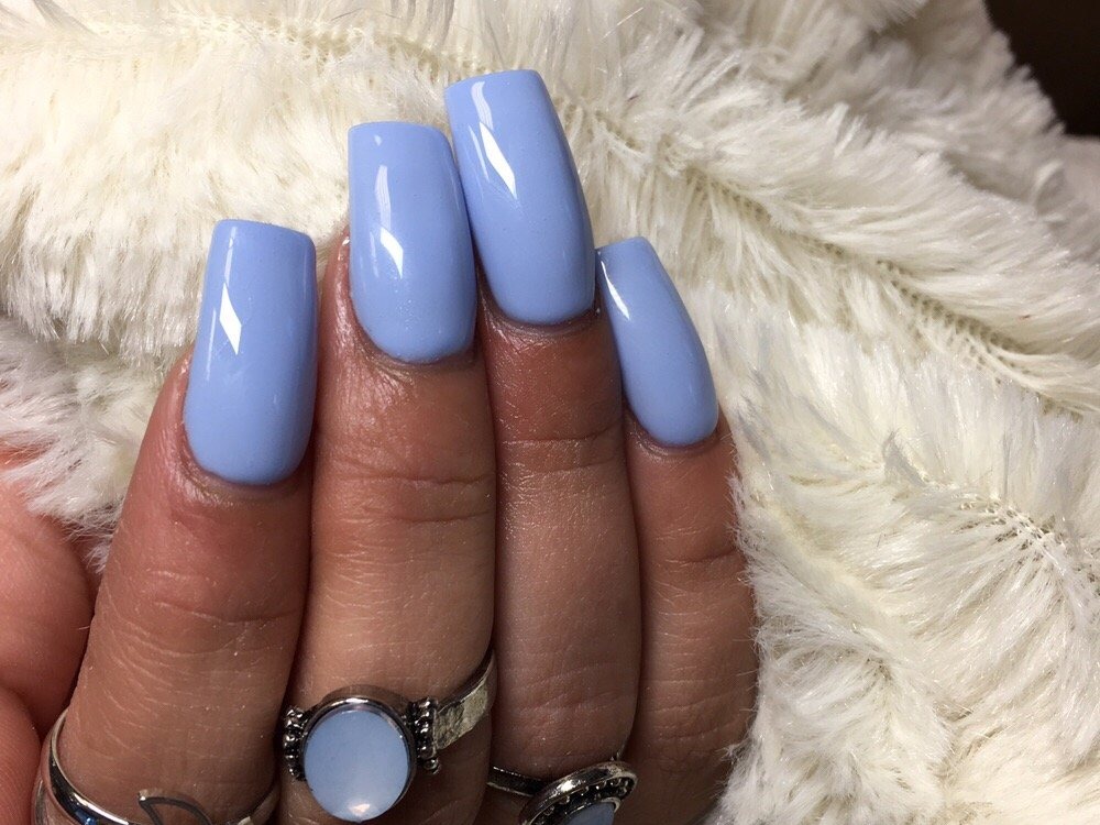 Long square nails in glossy periwinkle blue against white faux fur